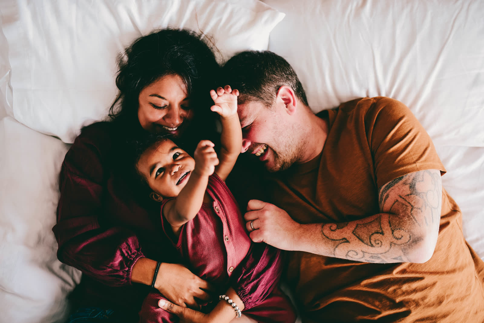 A family laughing on a bed with their toddler